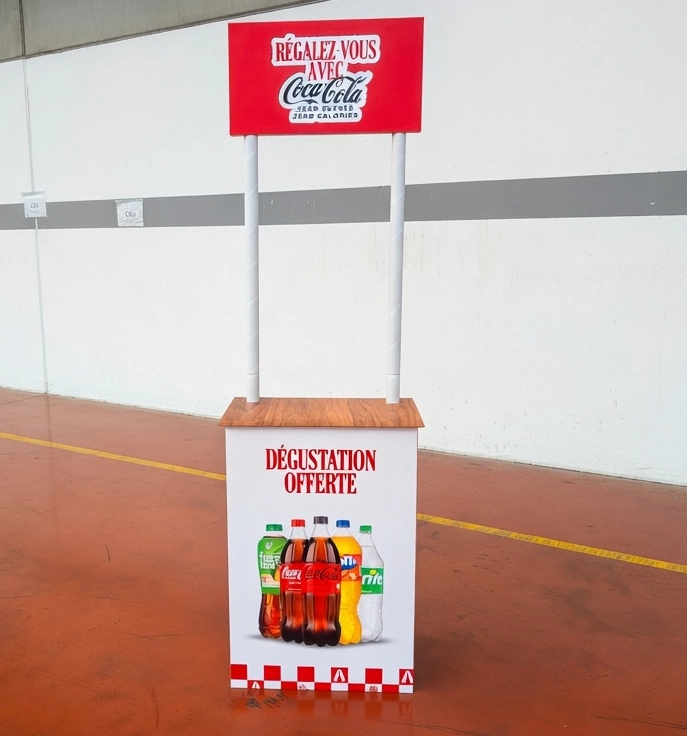 Stand de dégustation Coca-Cola monté en contrôle qualité dans l'atelier Kontfeel : ceinture, plateau effet bois, deux mâts blancs et fronton