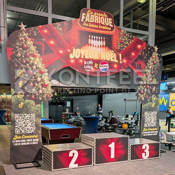 Arche événementielle autoportante conçue sur mesure : structure PLV grand format avec découpe à la forme et podium pour animation commerciale de Noël.
